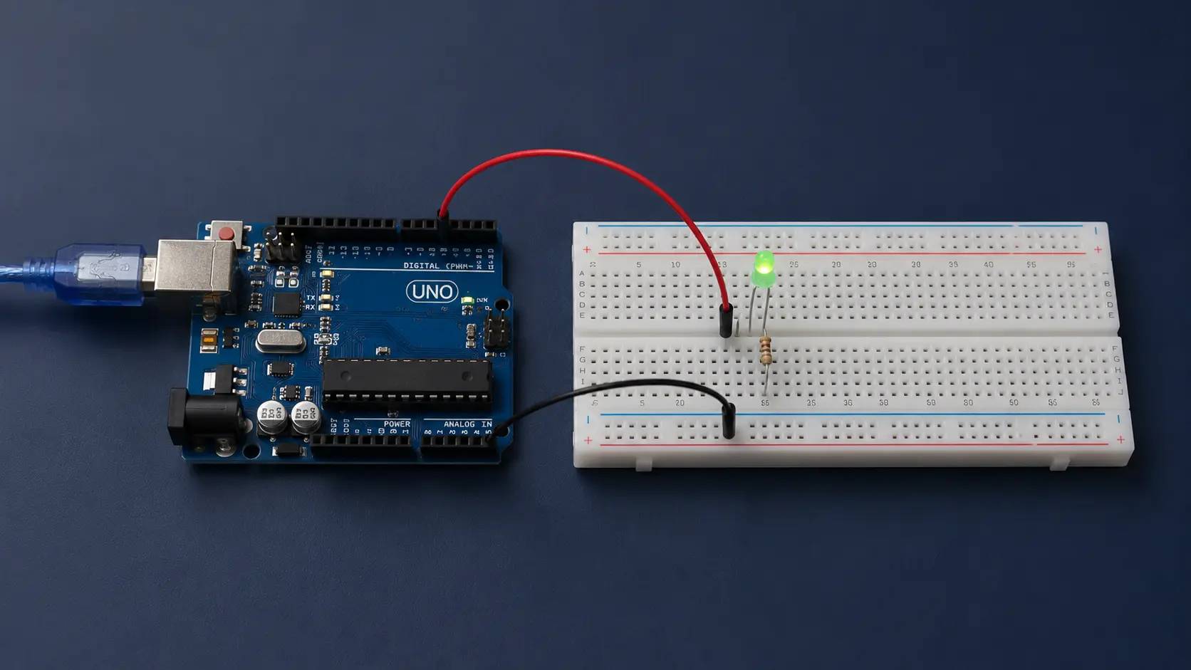 Representação fotográfica realista do projeto Fade-Out: Arduino Uno conectado a uma protoboard com LED verde, resistor de 220 ohms e dois jumpers; o LED aparece com brilho reduzido e não há pessoas.
